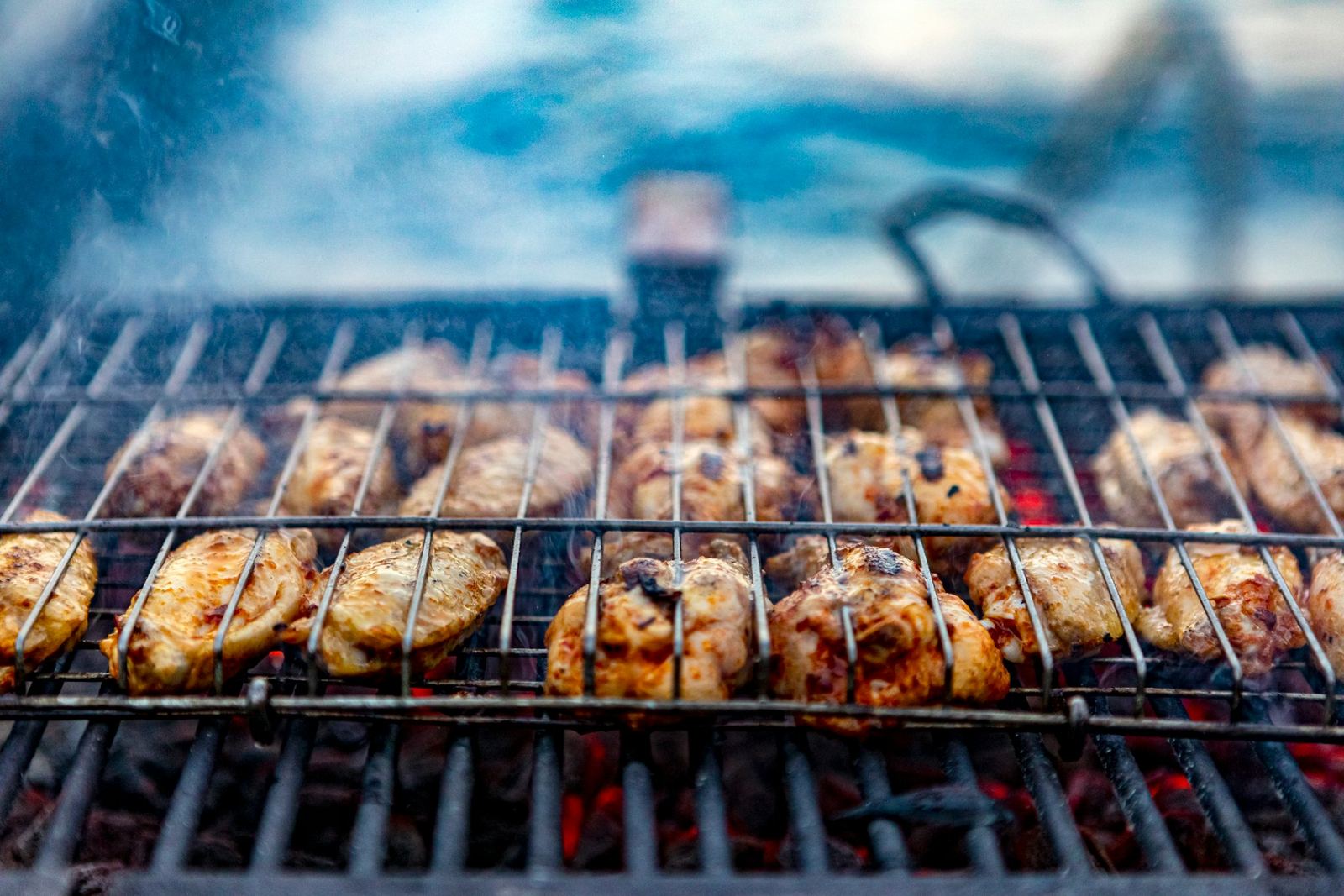 Rows of chicken pieces browning on a grill