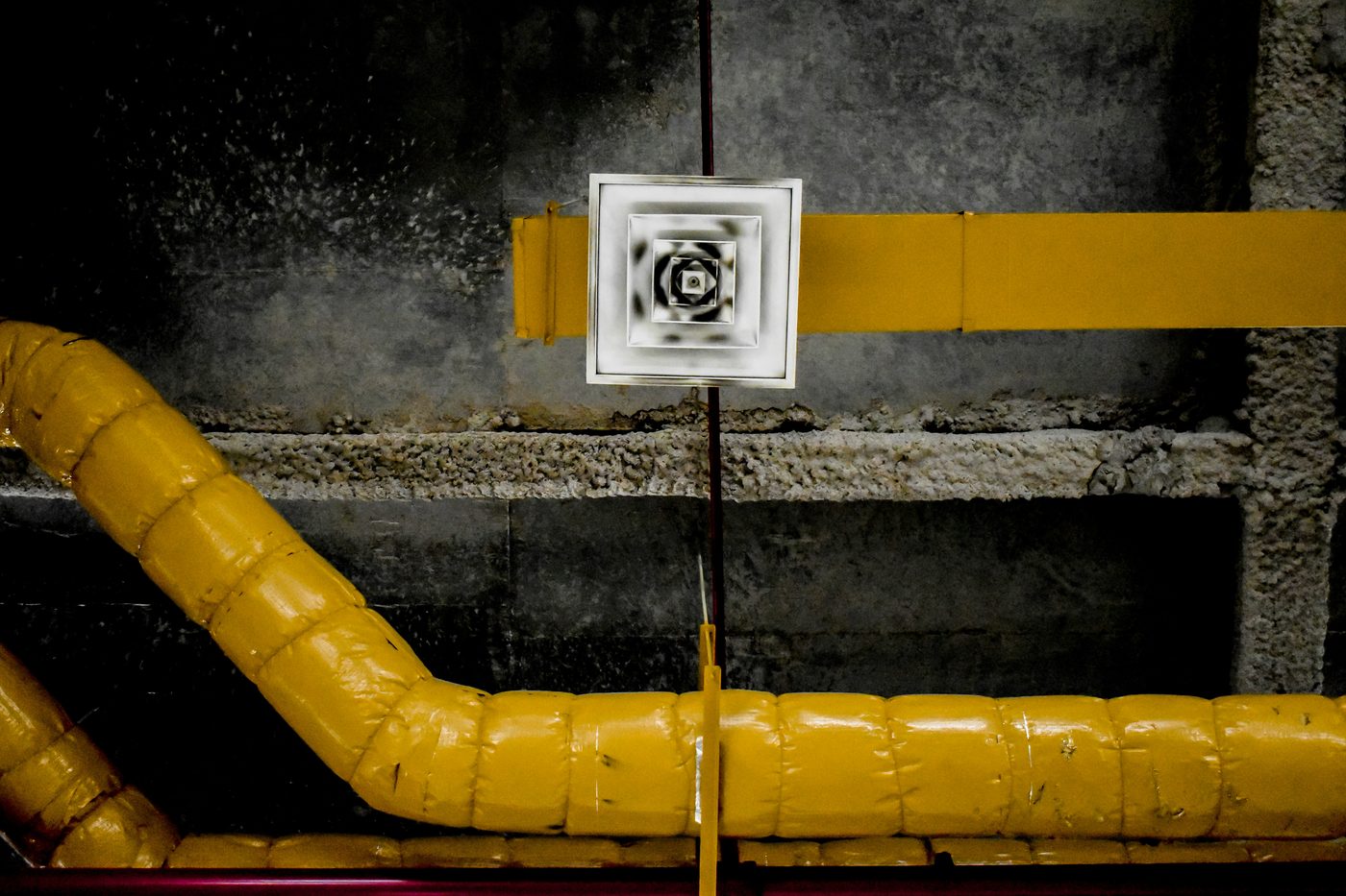 Yellow insulated ductwork running to a square ceiling vent