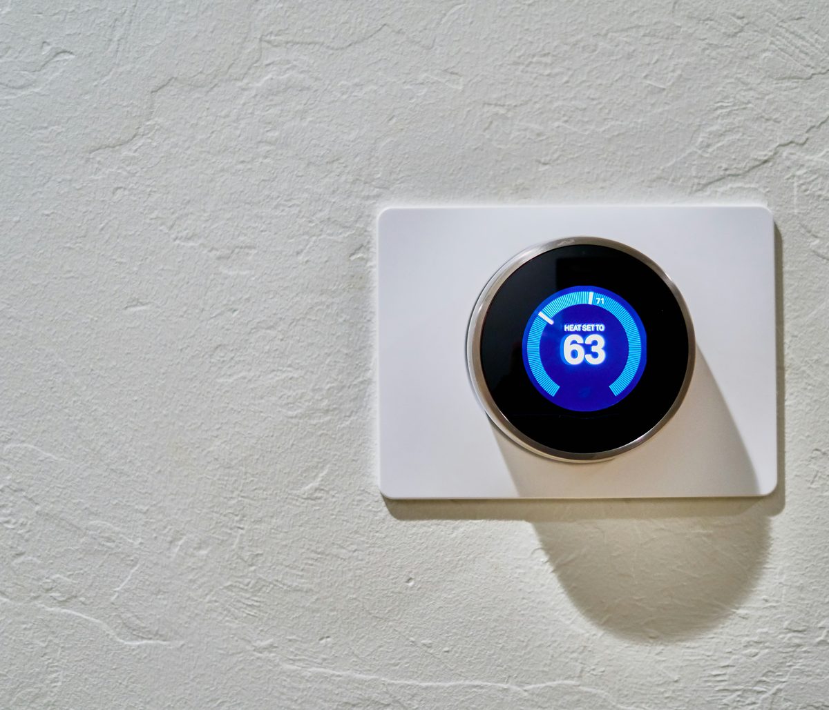 A round wall thermostat showing a heating set point of 63