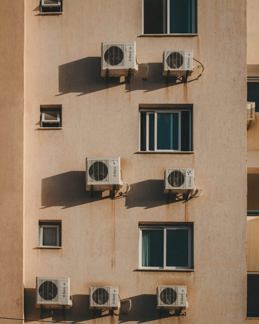 Several small air conditioning units mounted on an apartment wall