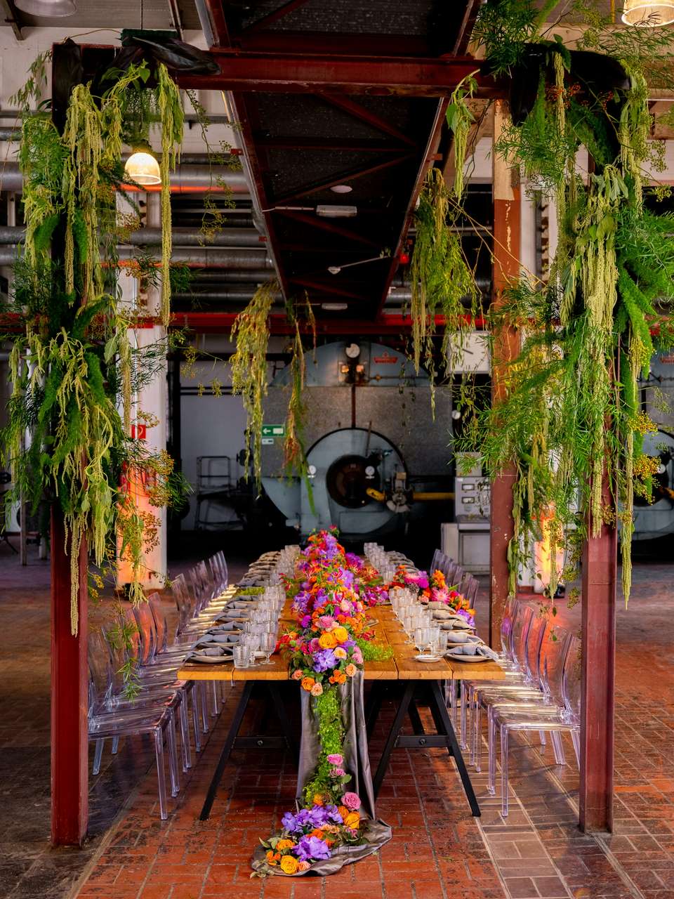A long dinner table in a tall hall, dressed with a trailing garland of flowers